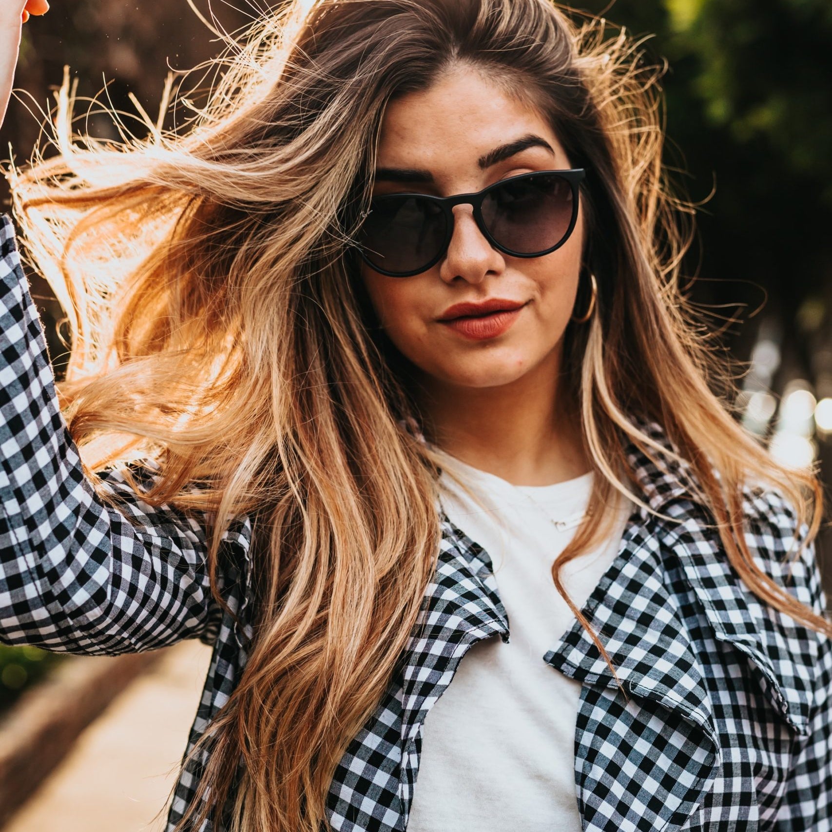 A woman in a checked coat and shades sporting long, elegant hair