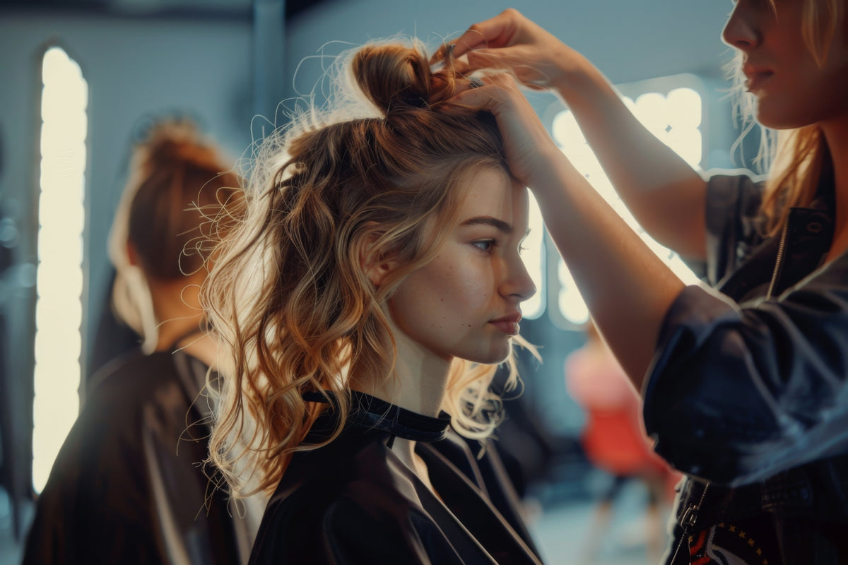 Woman getting her hair styled by a professional in a salon setting.