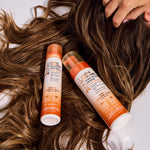 Two bottles of Elvive Ultra Care shampoo and conditioner on wet hair with a hand touching the hair.