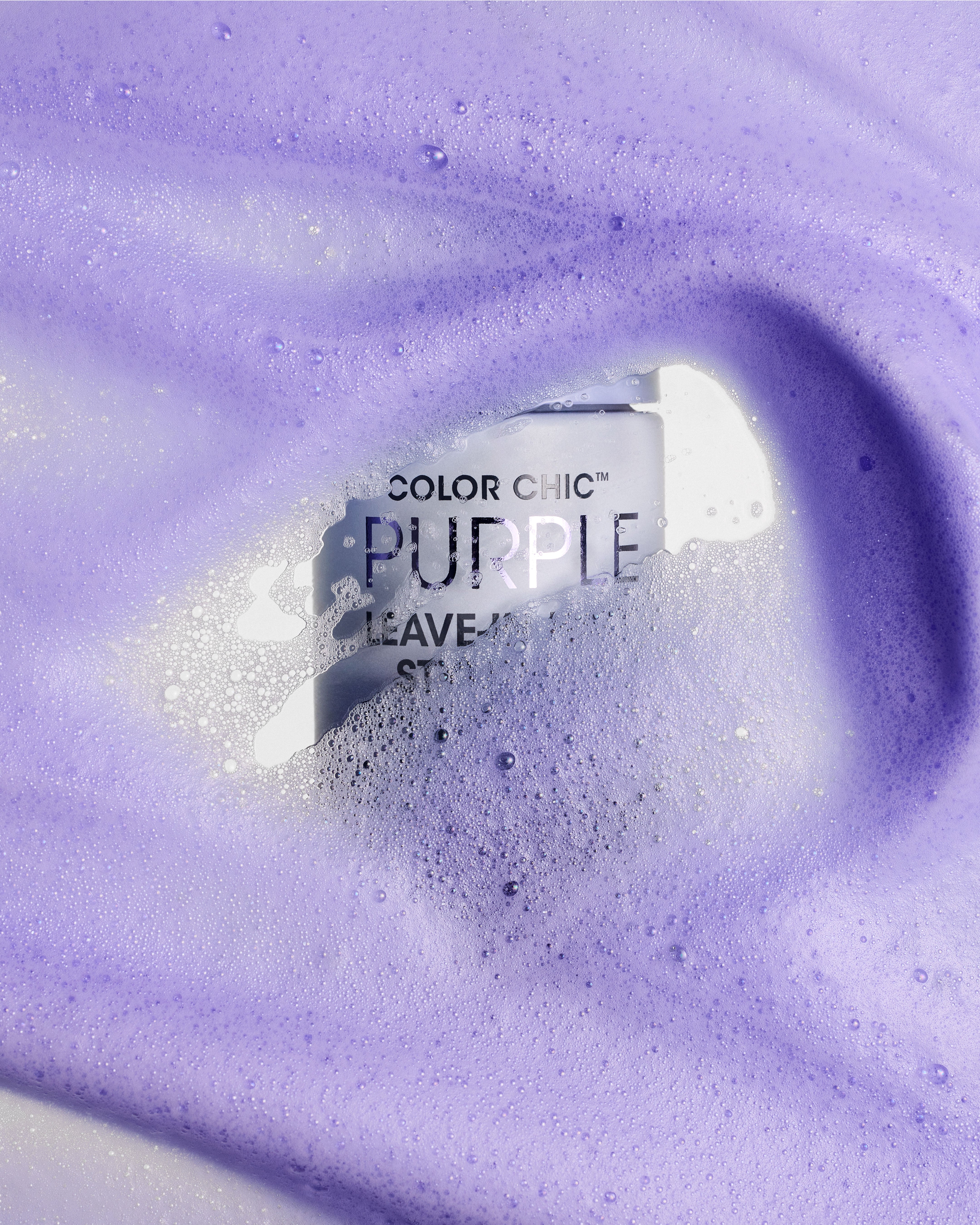 A bottle of Giovanni Cosmetics COLOR CHIC™ PURPLE LEAVE-IN HAIR STYLING & TONING FOAM, nestled in foamy lavender liquid rich in purple pigments and bubbles, helps neutralize brassy tones while providing a soft texture.