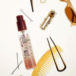 Flat lay featuring Giovanni Cosmetics 2chic® FRIZZ BE GONE™ ANTI-FRIZZ POLISHING SERUM, a tortoiseshell comb, sunglasses, hairpins, clips, and hair ties arranged on a white background.