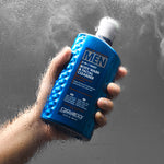 Hand holding a blue bottle of Giovanni Men's body wash against a gray background