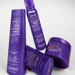 Four Giovanni Cosmetics CURL HABIT™ Curl Defining Shampoos in purple bottles, designed to moisturize and define curls, are arranged on a white surface.