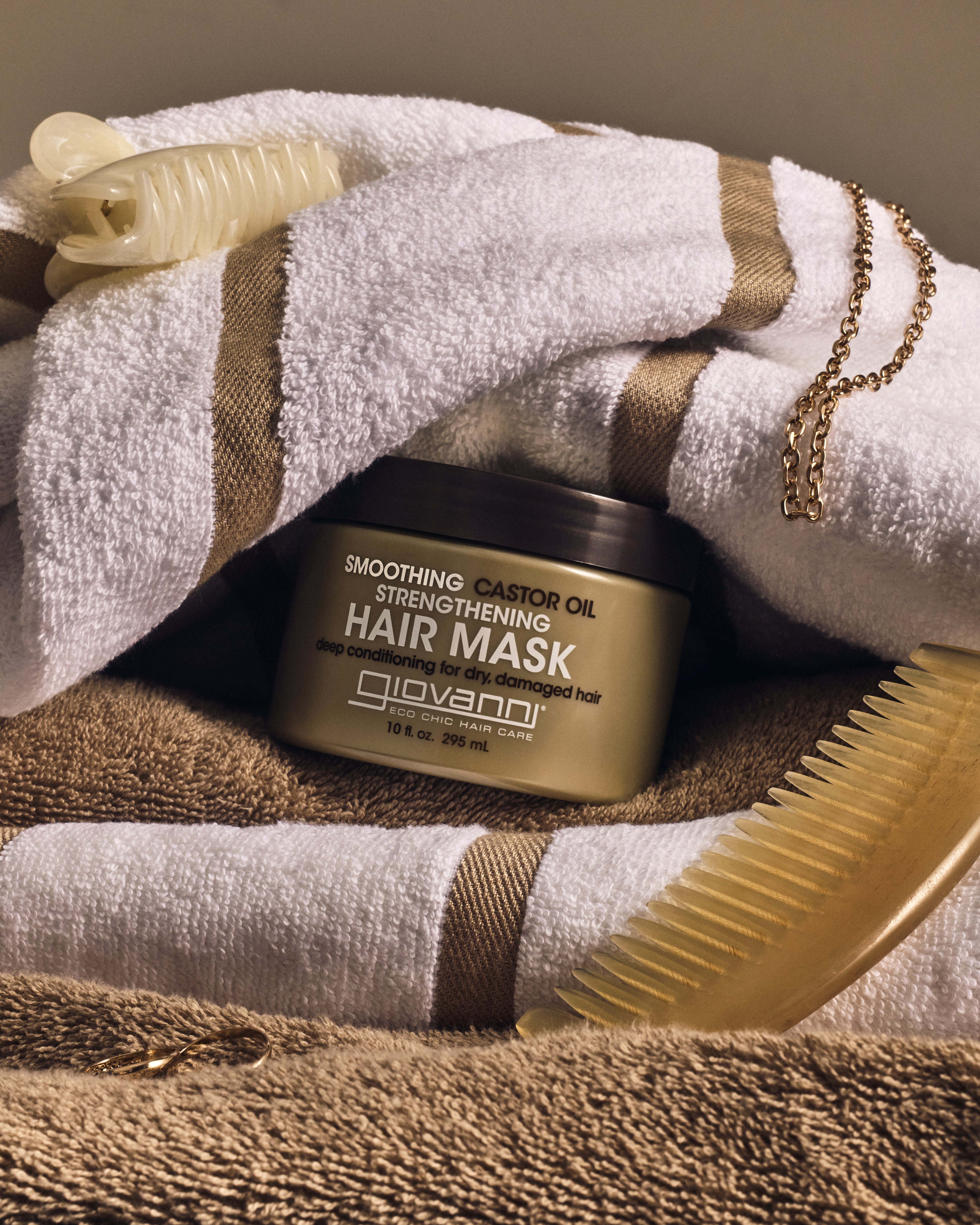 Image of Smoothing Castor Oil Strengthening Hair Mask snuggled in bath towels. 