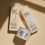 Three Giovanni Smooth As Silk haircare products in white packaging are arranged diagonally on a warm beige surface with soft diagonal shadows.