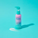 A pink and turquoise pump bottle from the Giovanni Cosmetics KIDs Bundle sits on a turquoise surface with a small amount of white product beside it, perfect for pairing with your favorite detangling spray or 2-in-1 shampoo and conditioner.