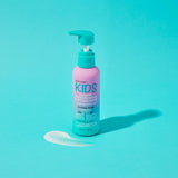 A pink and turquoise pump bottle from the Giovanni Cosmetics KIDs Bundle sits on a turquoise surface with a small amount of white product beside it, perfect for pairing with your favorite detangling spray or 2-in-1 shampoo and conditioner.