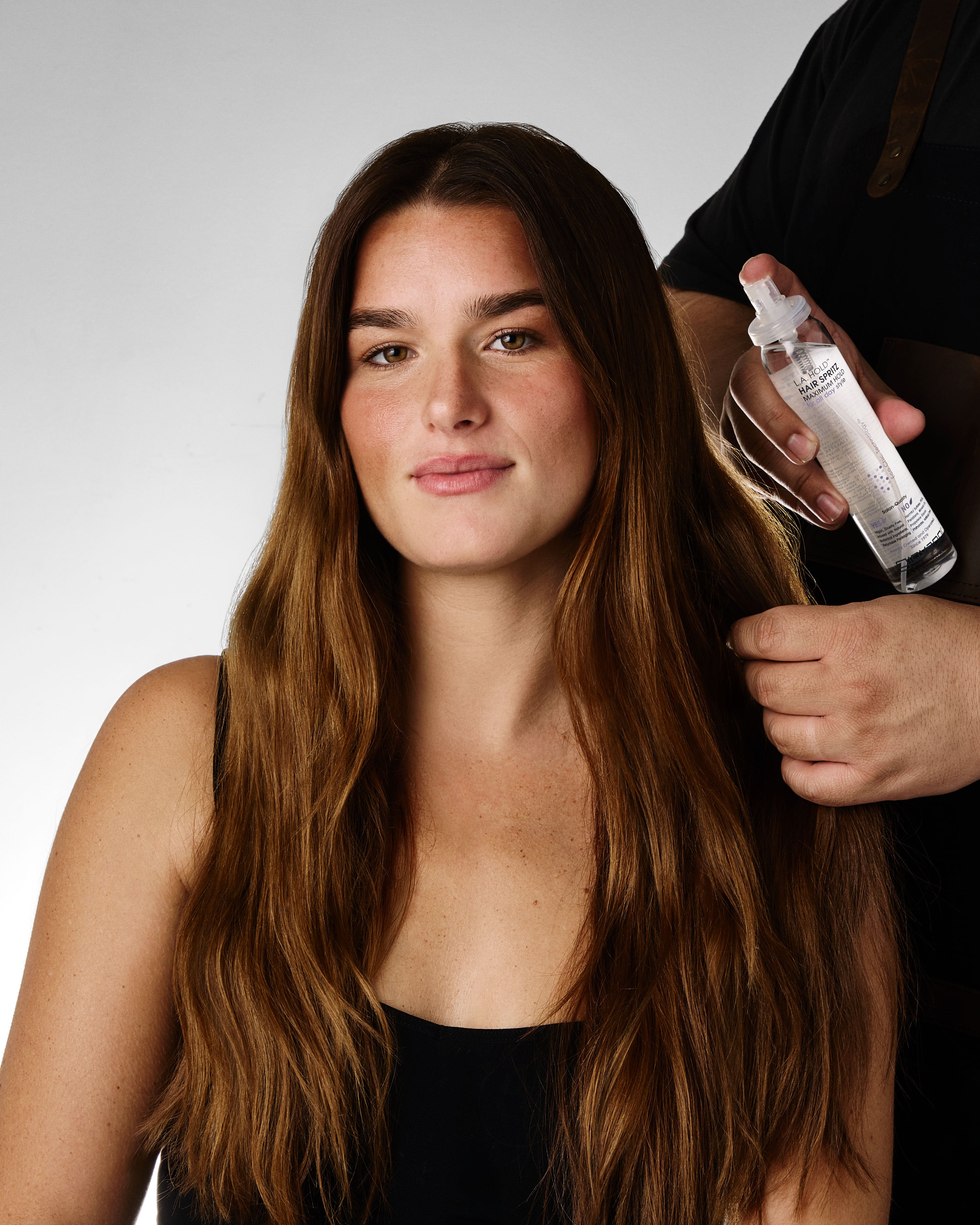 Woman with long hair getting Giovanni LA Hold Hair Spritz applied