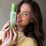 Model holding up Giovanni's Ultra-Moist Dula-Action Protective Leave-In Spray. She has blowdried hair with soft curls