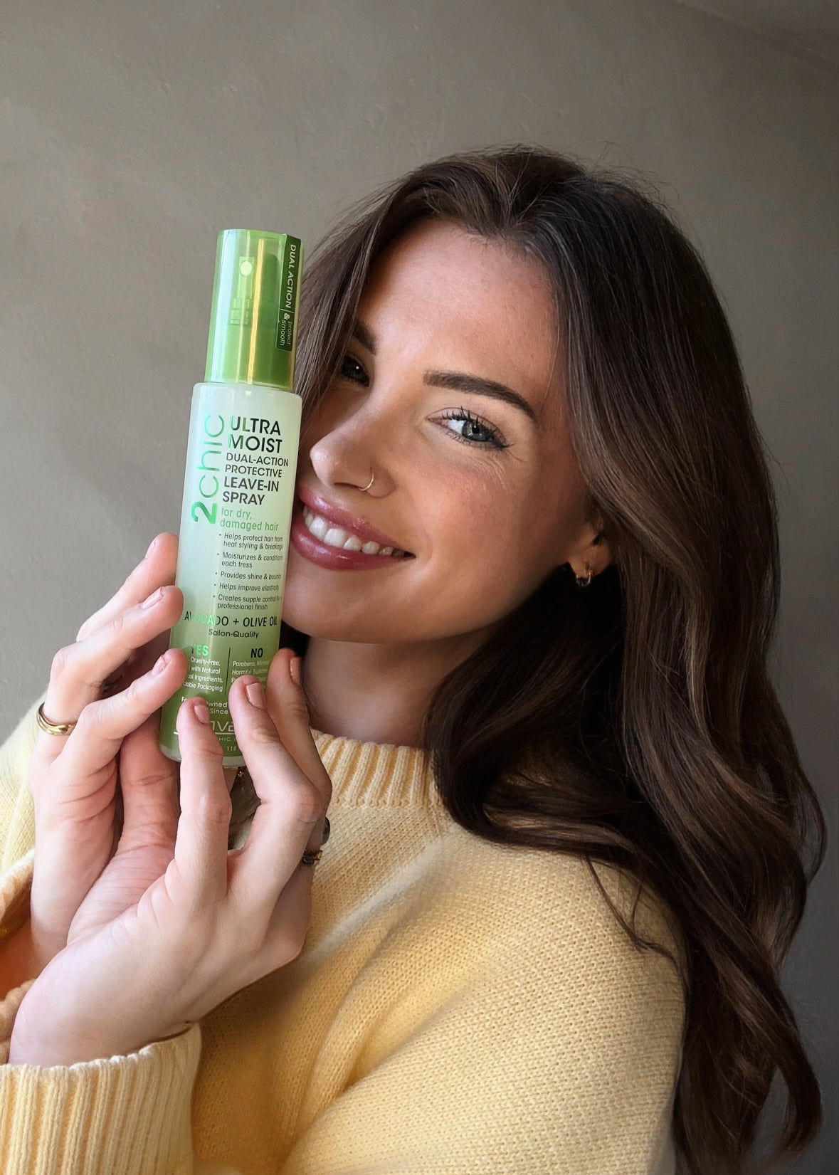 Model holding up Giovanni's Ultra-Moist Dula-Action Protective Leave-In Spray. She has blowdried hair with soft curls