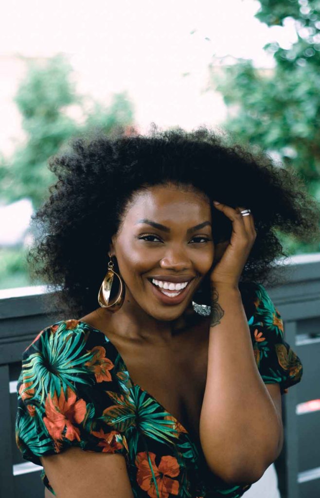 A woman with natural hair volume in a tropical top.