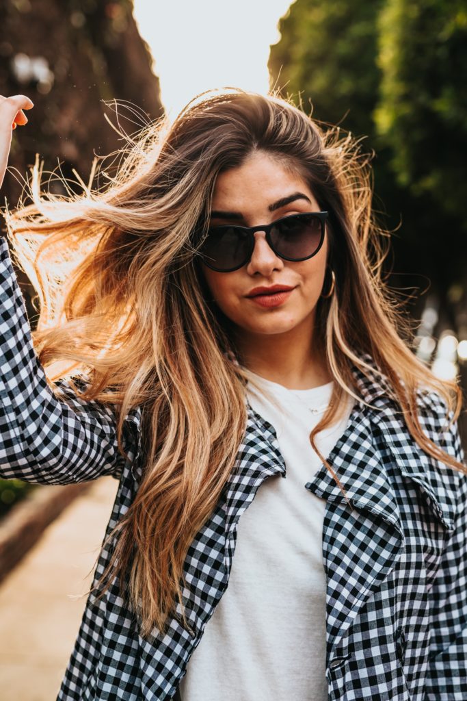 A woman in a checked coat and shades sporting long, elegant hair