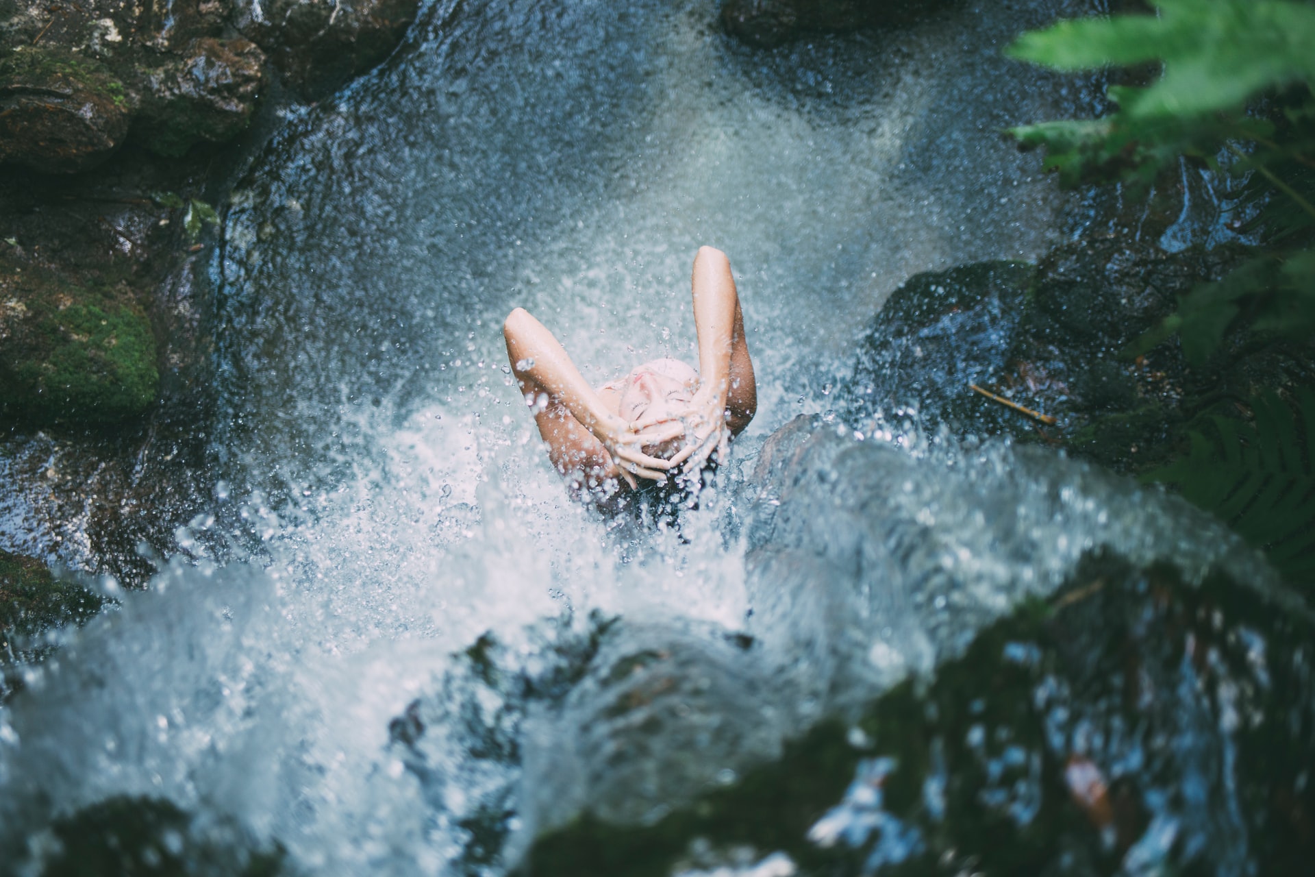 A woman washing her hair in a waterfall.